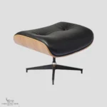 Close-up of a Charles Ray Eames style ottoman featuring black upholstery and a black-powder coated base.